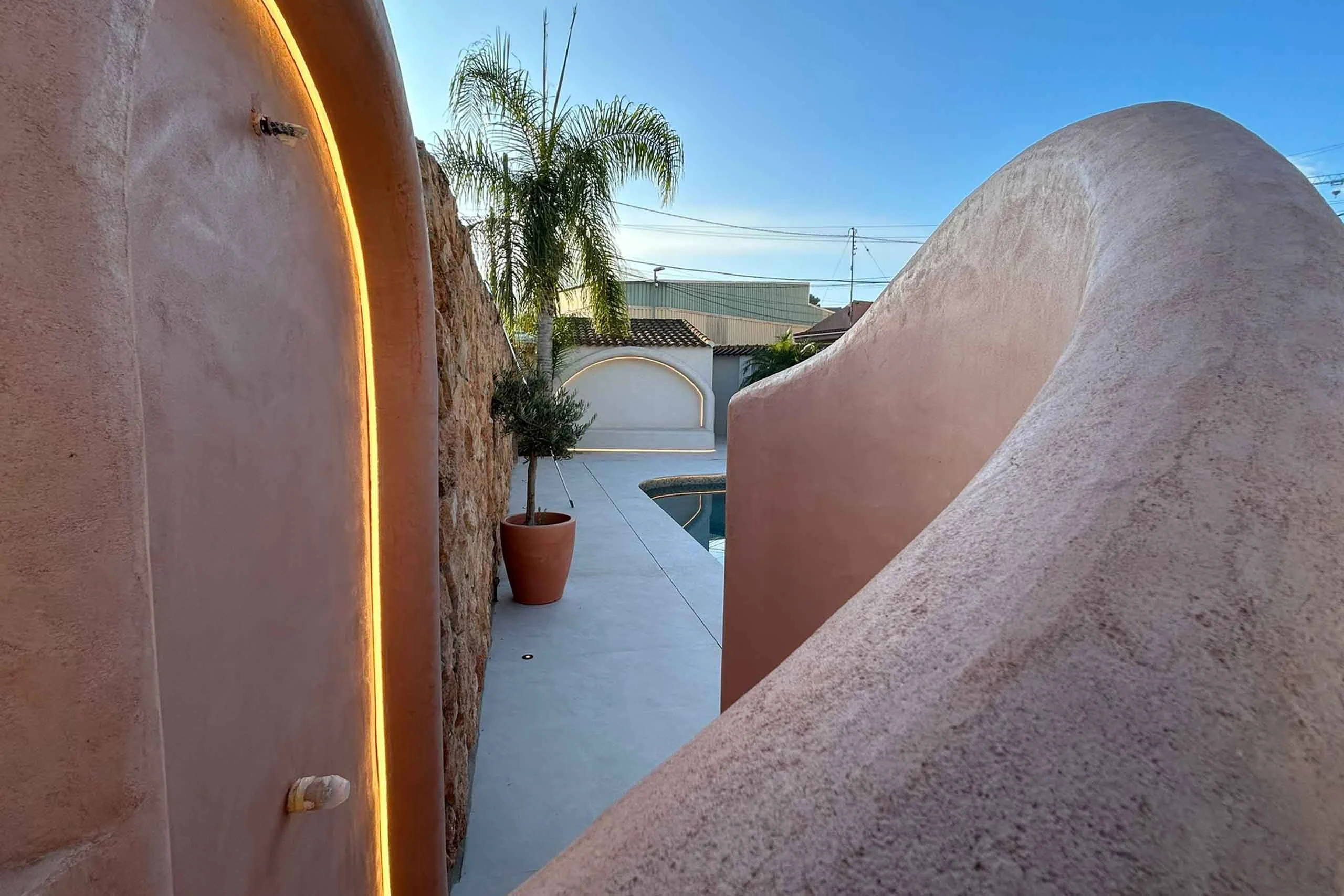 Muro curvo revestido con cal junto a una piscina