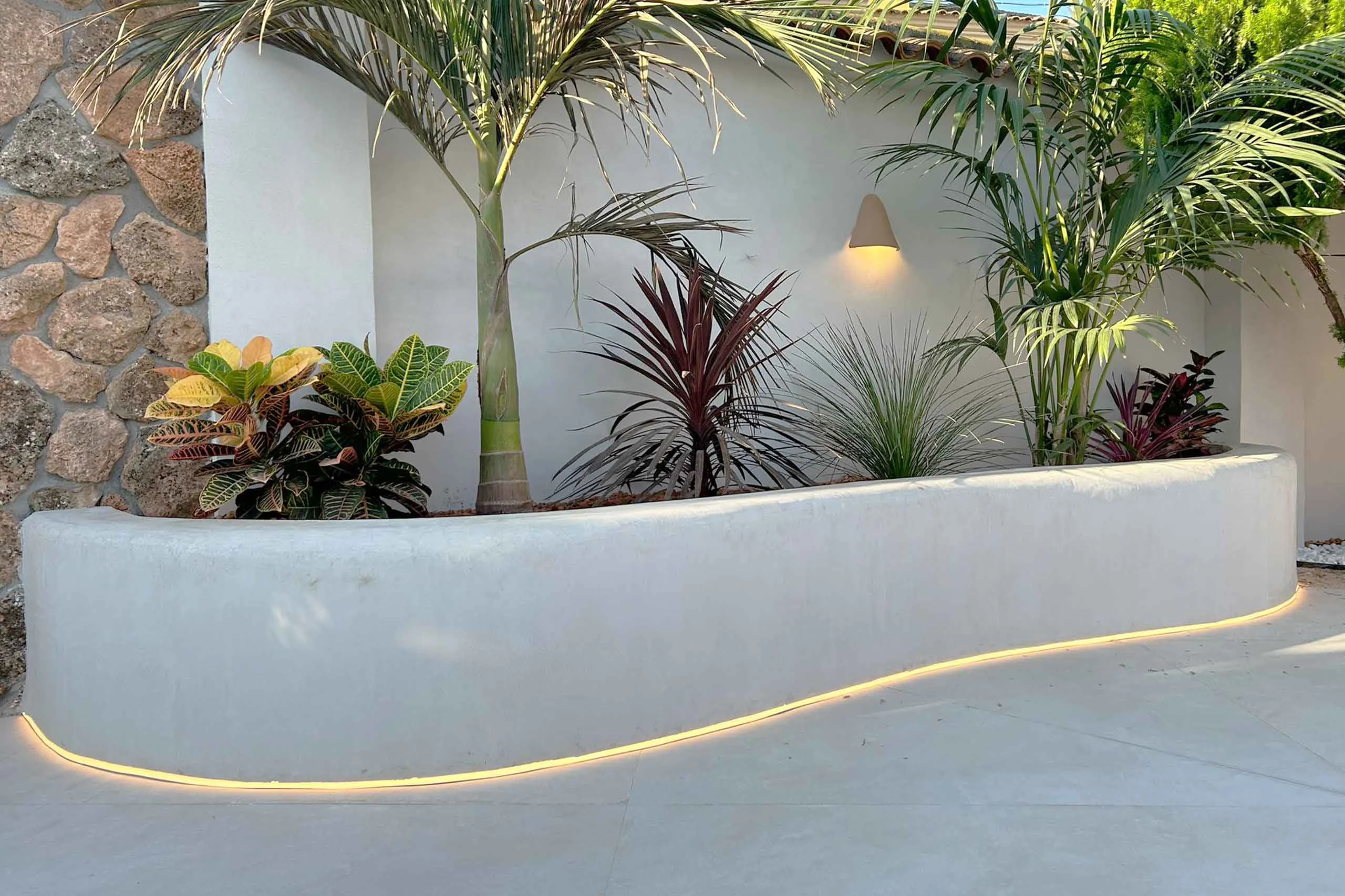 Jardinera curva revestida con cal e iluminación integrada