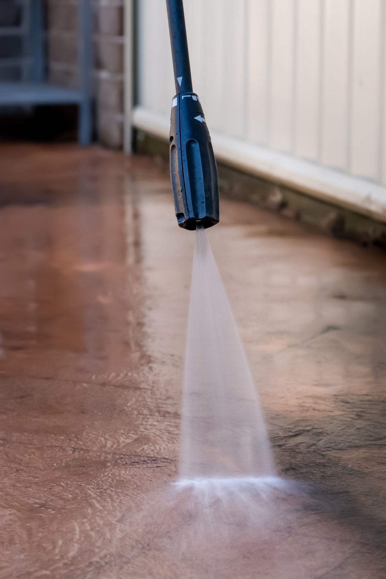 Washing dirty backyard tiles with high pressure cleaner. Spring clean up